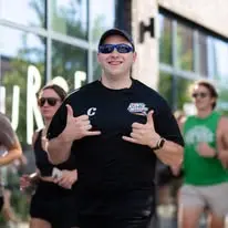 Joseph smiling outdoors in a Northeast Running Club shirt