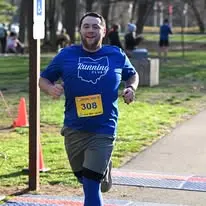 Joseph running a race in a blue Northeast Running Club shirt